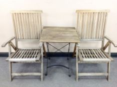 A teak and metal folding garden table and a pair of chairs