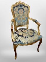 A Continental gilt wood and gesso salon armchair in studded blue floral upholstery