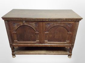 An early 20th century Continental carved oak double door fall front cabinet,