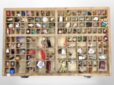 A printer's type tray containing a quantity of figurines and trinkets,