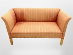 A 20th century Danish two seater settee in striped orange upholstery,