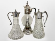 Two glass claret jugs with silver plated mounts together with a further glass decanter on stand.