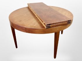A teak circular dining table with three leaves