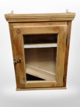 A glazed pine single door wall cabinet,