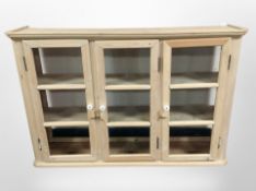 An early 20th century pine glazed triple door wall cabinet,