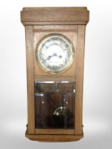 An early 20th century oak 8-day wall clock with silvered dial.
