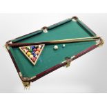 A table top pool table, with cues and balls,