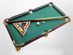 A table top pool table, with cues and balls,