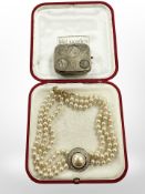 An antique silvered brass coin case and a costume pearl triple strand necklace.