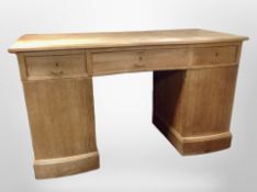 An early 20th century Danish oak serpentine front twin pedestal desk, width 140cm.