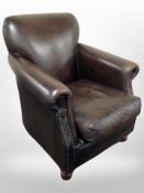 A contemporary Thomas Lloyd brown studded leather armchair on bun feet