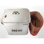 A vintage enameled bread bin containing wooden clothes pegs.