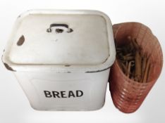 A vintage enameled bread bin containing wooden clothes pegs.