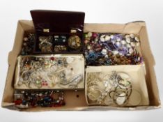 A box of assorted costume jewellery, gold-plated chains and bangles, bead necklaces, brooches.