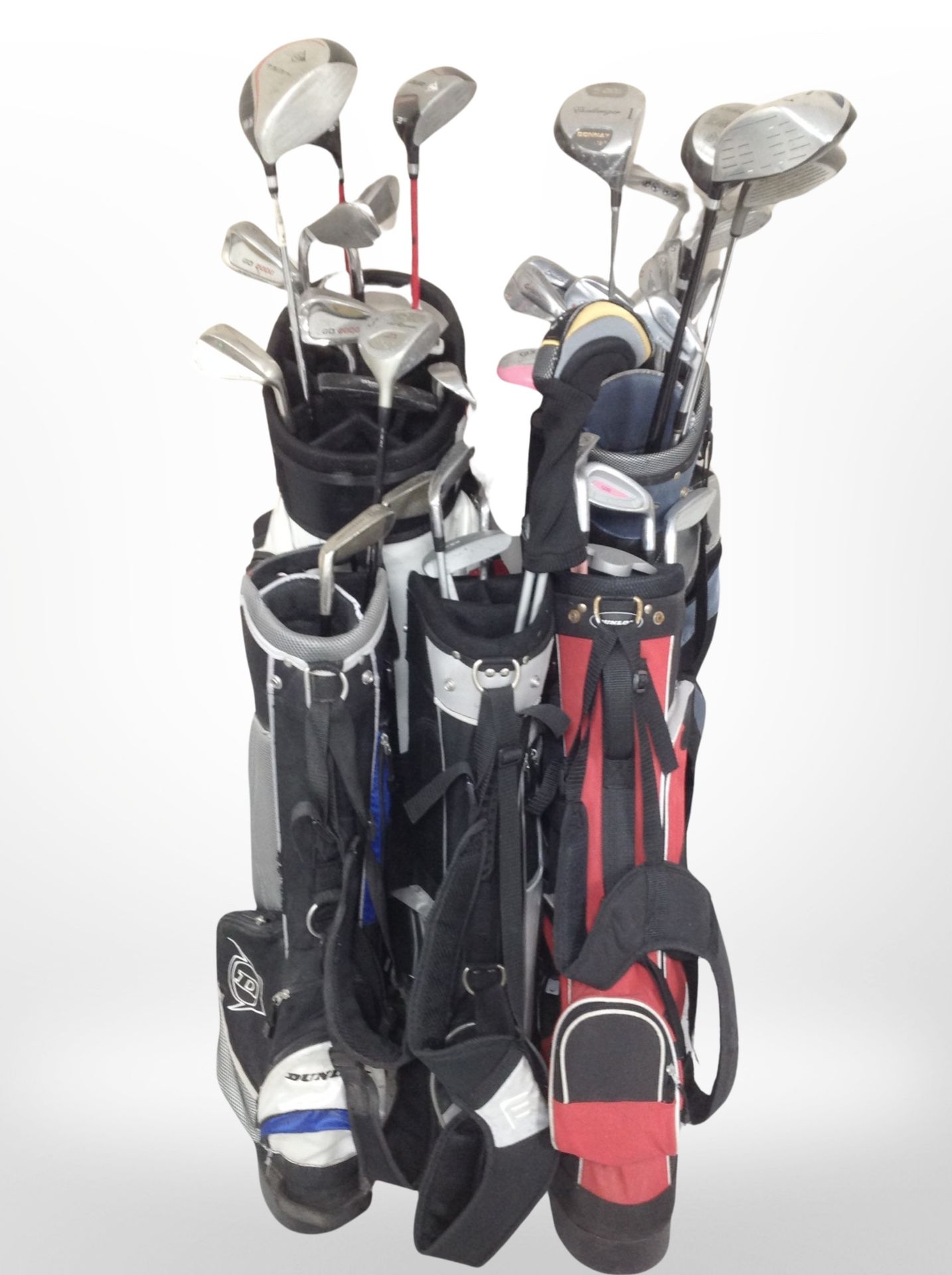 Several golf bags containing assorted drivers and irons including Donnay, Masters,