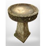 A weathered concrete pedestal bird bath,