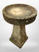 A weathered concrete pedestal bird bath,