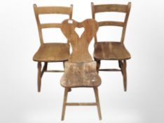 A pair of early 20th century pine dining chairs and one other with carved heart back rest