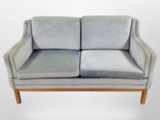 A late 20th century Danish two seater settee upholstered in sky blue fabric,