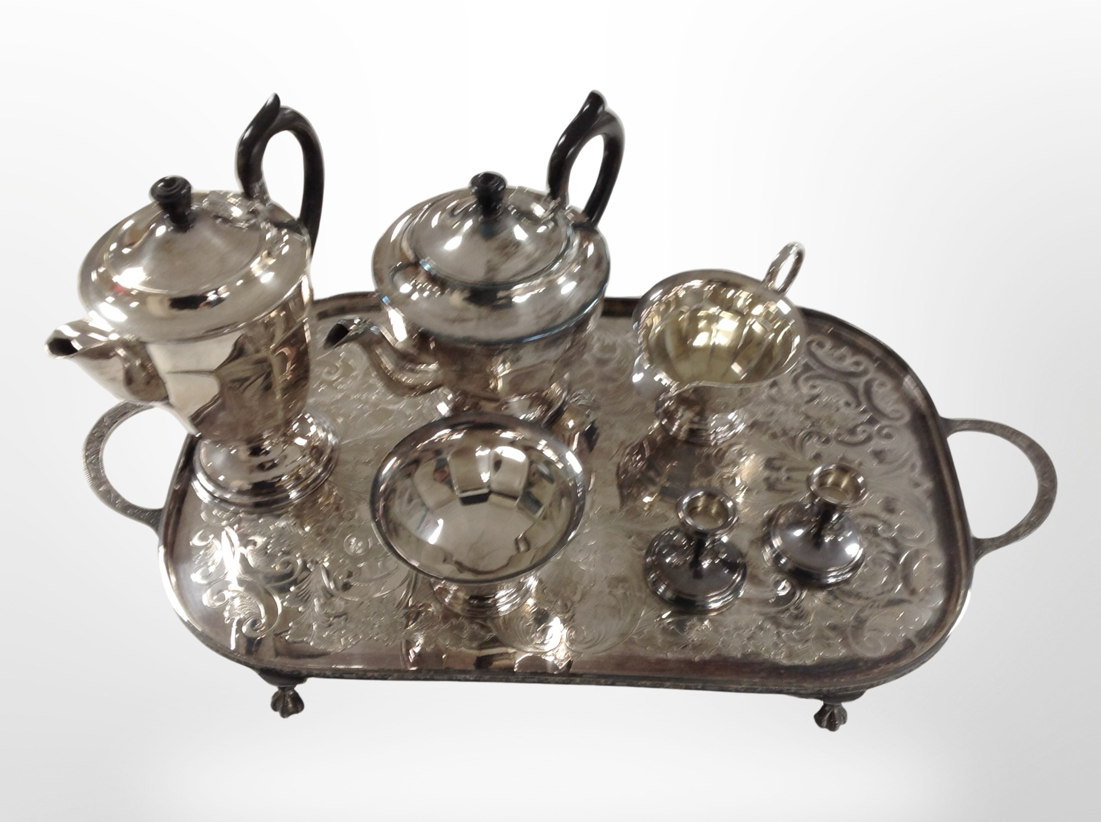 A silver-plated four-piece tea service on tray, and a further pair of dwarf candlesticks.