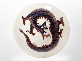 A William Moocroft plate decorated with a dragon, diameter 26 cm.