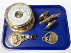 A brass-cased circular barometer, two horse brasses, and a miniature cannon.