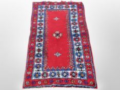 An Eastern wool rug on red ground,