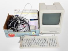 A vintage Macintosh SE computer with keyboard and a box containing related ephemera, manuals, etc.