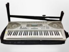 A Casio TK-900 digital keyboard on stand with carry case.