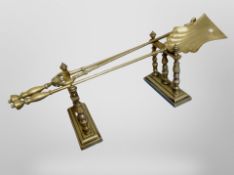 A pair of Victorian brass firedogs, together with a pair of tongs and a shovel.