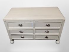 An early 20th century painted low six drawer chest on bun feet,