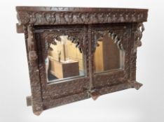 An Eastern heavily carved overmantel mirror,