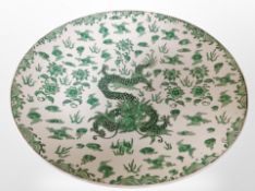 A 20th century Chinese porcelain charger decorated in green enamels with a five-clawed dragon