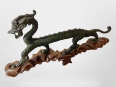 A 20th century Chinese patinated bronze dragon on hardwood stand, length 35cm.