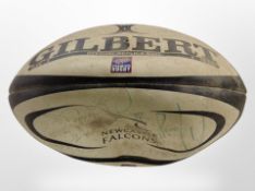 A Newcastle Falcons rugby ball with team signatures.