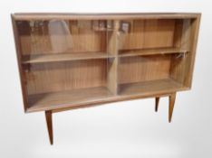 A teak open bookcase with sliding glass doors,