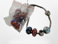 A Pandora bracelet with four beads and a bag of similar beads