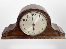 An Edwardian carved oak mantel clock with silvered dial, width 39cm.