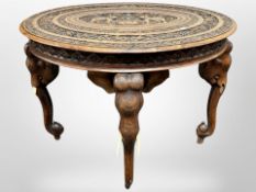 A Indian heavily carved hardwood oval occasional table, on elephant supports, 90 cm long,