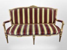 A French Louis XV style giltwood and gesso three seater salon seater in striped upholstery,
