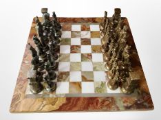 An onyx chessboard and set of cast metal chess pieces.