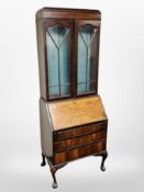 An early 20th century burr walnut veneered bureau bookcase on claw and ball feet,