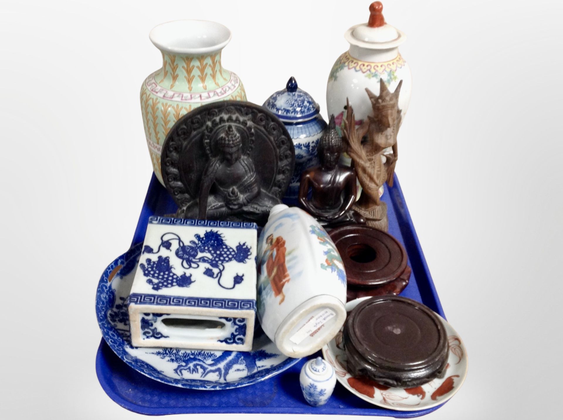 A tray of oriental wares including porcelain lidded vases, carved figures of Buddha,