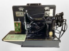A Singer 221K electric sewing machine in box with instructions and tin of Singer sewing machine oil.