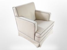 An early 20th-century armchair in cream fabric.