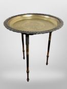 An engraved brass-topped circular tripod table, height 47cm.