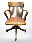 A 1920s oak swivel office armchair with studded vinyl seat.