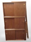 A 1970s teak modular wall unit comprising three sliding-door cupboards, three shelves, and supports,