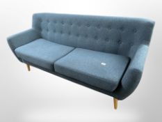 A contemporary Danish three-seater settee in buttoned blue upholstery on tapered beech legs,