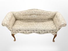 An early 20th-century window seat on carved cabriole legs upholstered in tasselled floral fabric,